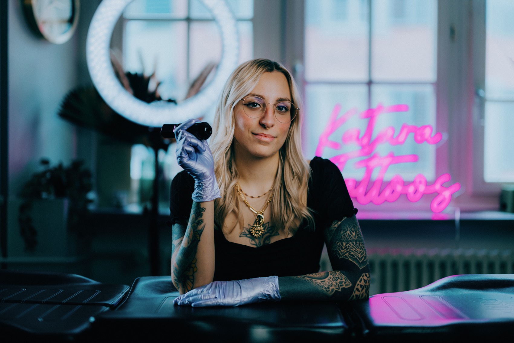 Katara mit Tattoomaschine vor dem Katara-Tattoos-Neonschild